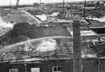 Gevolg van het bombardement op 21 juni 1940 door de Royal Air Force. Op de voorgrond het getroffen Marinehospitaal, dat nog wordt geblust en daarachter de Rijkswerf Willemsoord met het opgelegde pantserschip Hertog Hendrik. Bron: NIMH